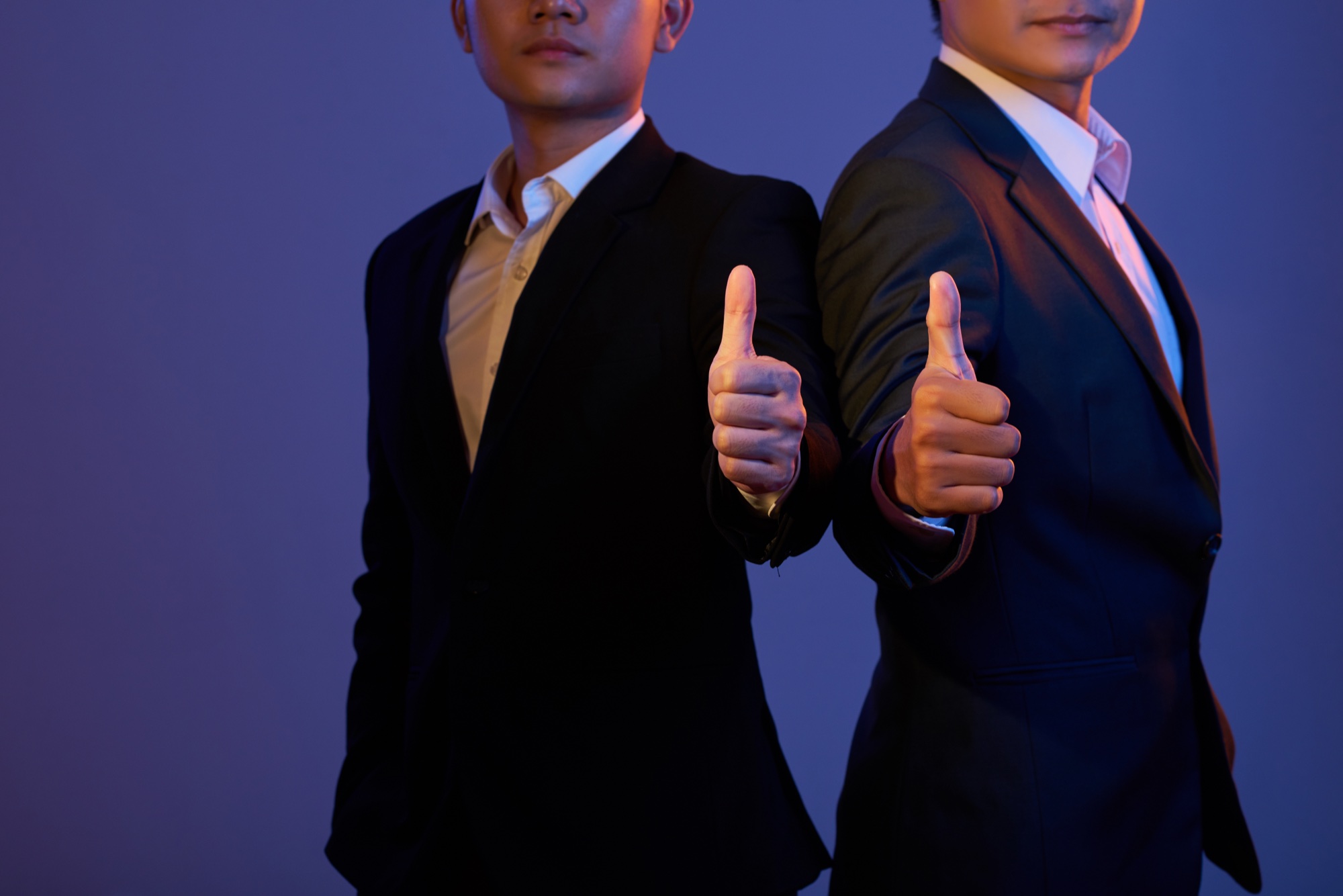 Two business partners giving thumbs up in suits